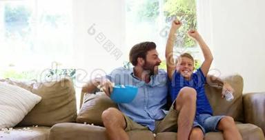 快乐的父亲和儿子在电视前享受